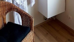 A bathroom with a white sink, a mirror, and a wicker chair. - Harbour Inn guesthouse (Vesturbyggð)