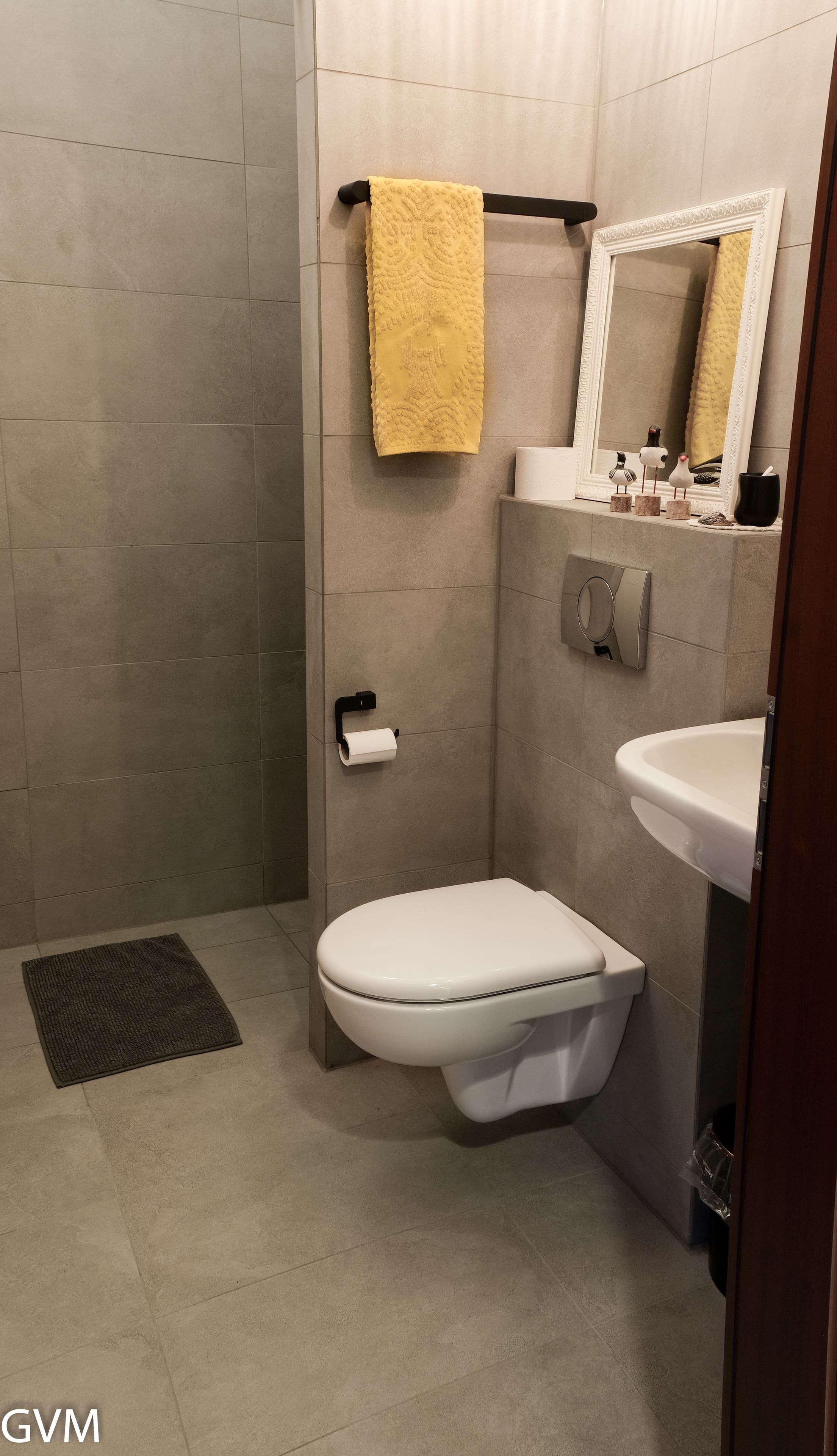 A modern bathroom with a toilet, sink, and mirror.