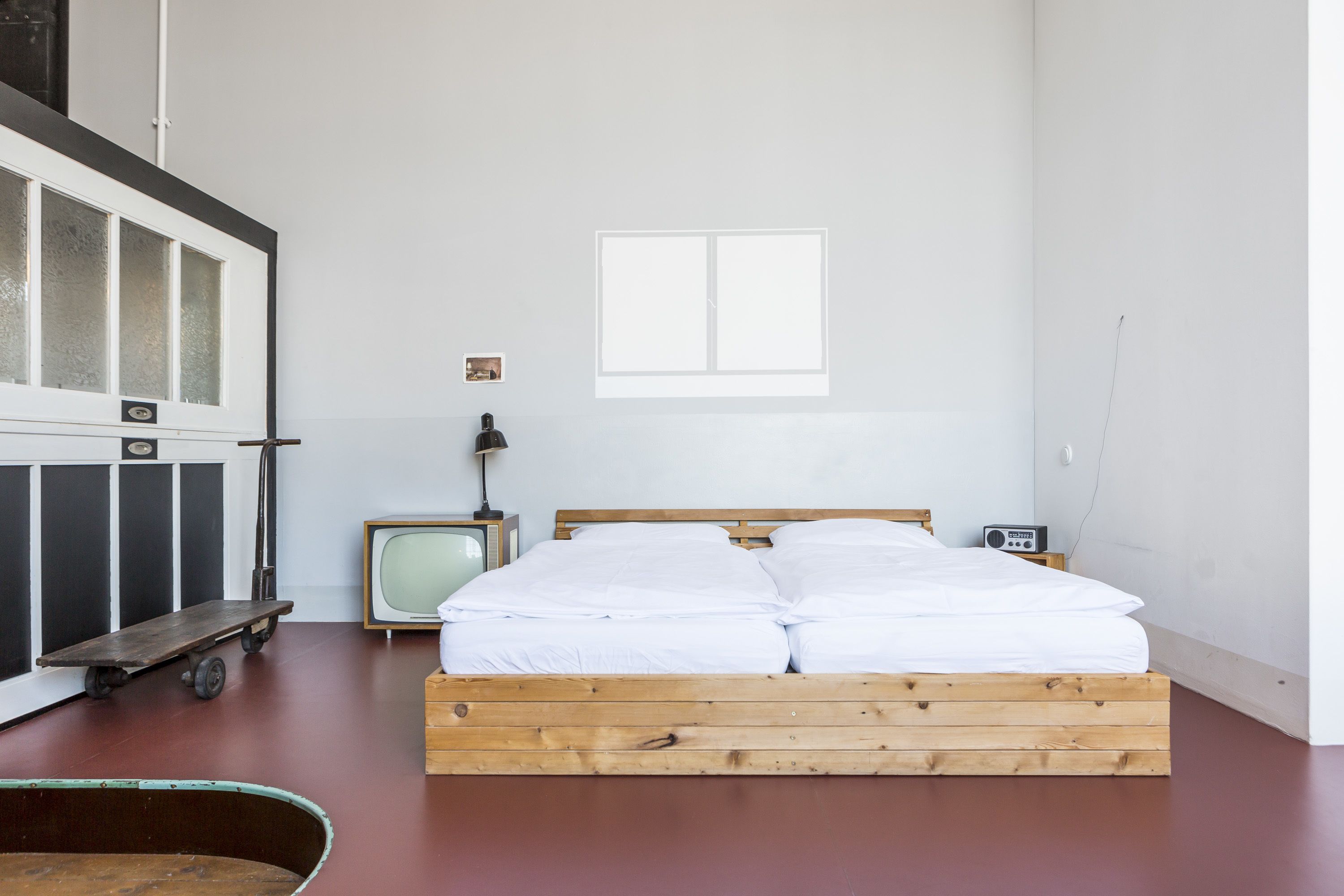 Ein schlichtes Schlafzimmer mit einem hölzernen Bett, einem alten Fernseher und einem kleinen Tisch.