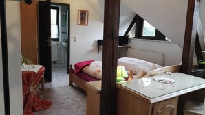 A bedroom with a bed, a bedside table, a window, and a view of a bathroom. - Radler-Scheune Thüringen (Friedrichroda)