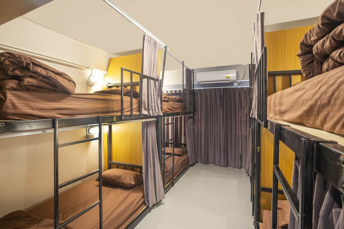 Ein Schlafsaalzimmer mit Etagenbetten, einem Fenster mit Vorhängen und einer wandmontierten Klimaanlage.