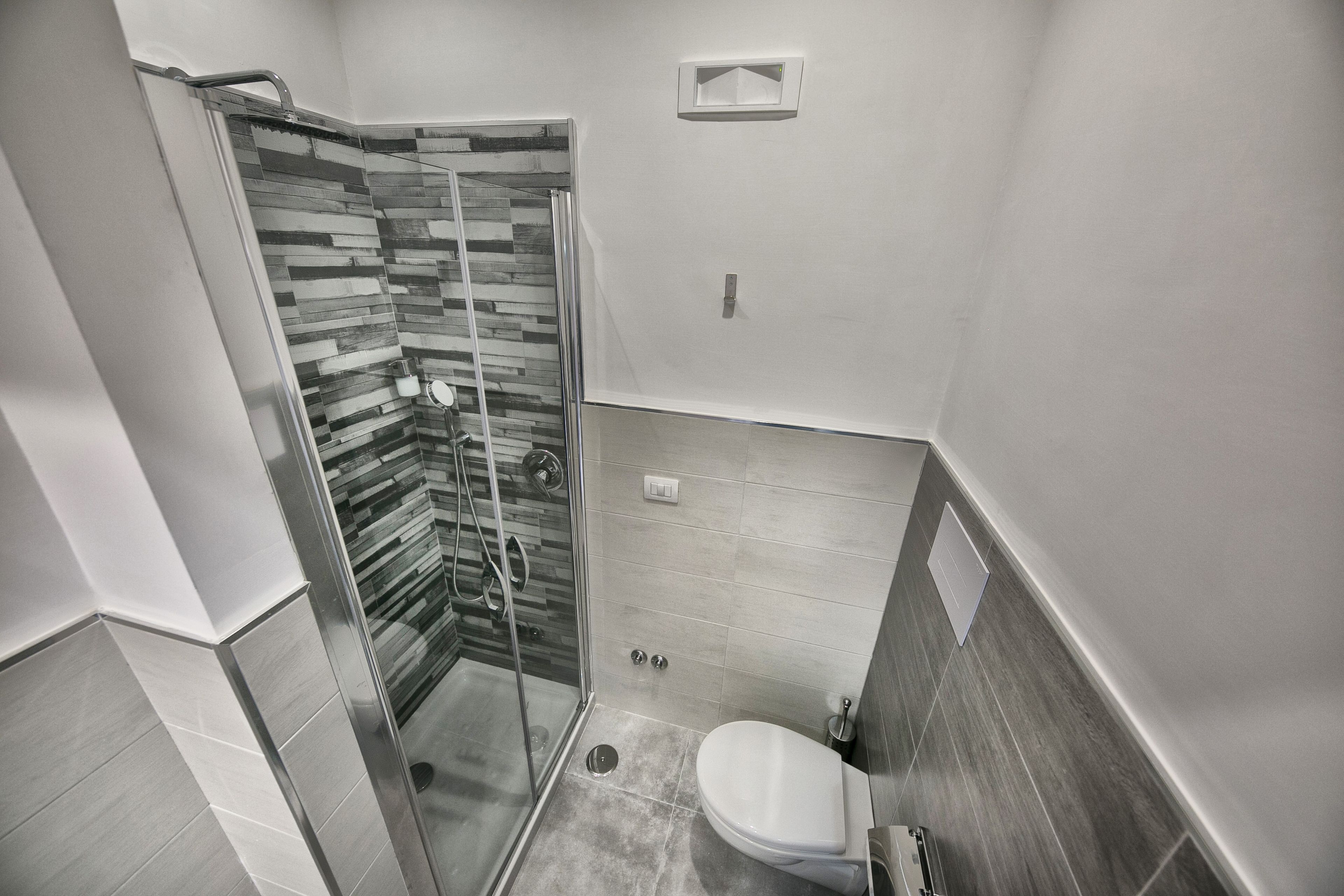 A modern bathroom with a glass shower enclosure, a toilet, and a sink.