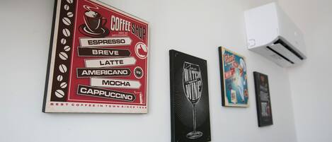 A wall with various framed items including a coffee shop sign and a wine glass sign.