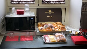 A breakfast buffet with pastries, a microwave, and a coffee machine.