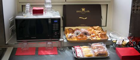 Un bufé de desayuno con pasteles, un microondas y una máquina de café.