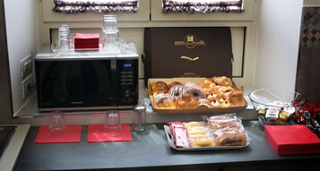 Un buffet de petit-déjeuner avec des viennoiseries, un four à micro-ondes et une machine à café.