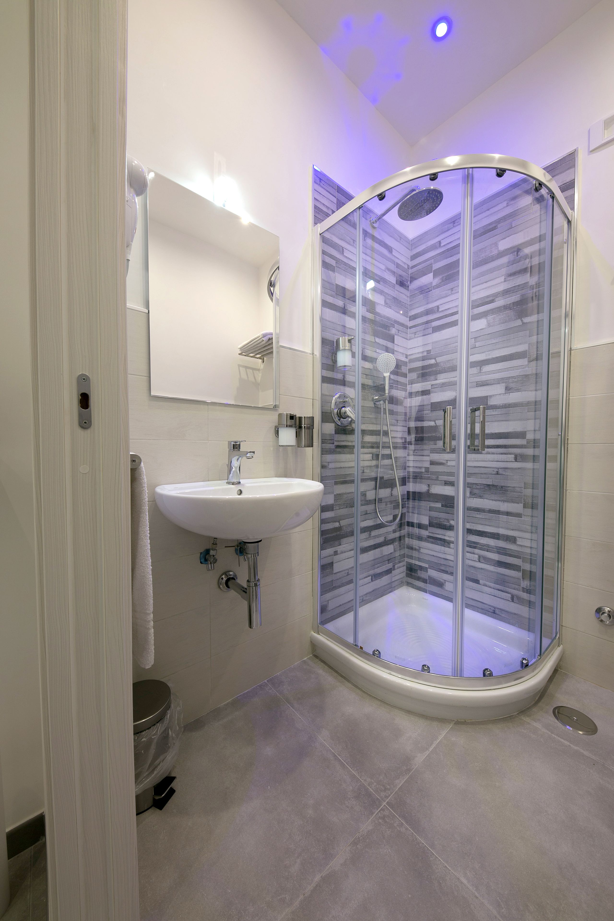 A modern bathroom with a glass-enclosed shower, a white sink, and a toilet.