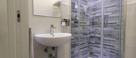 A modern bathroom with a glass-enclosed shower, a white sink, and a toilet.