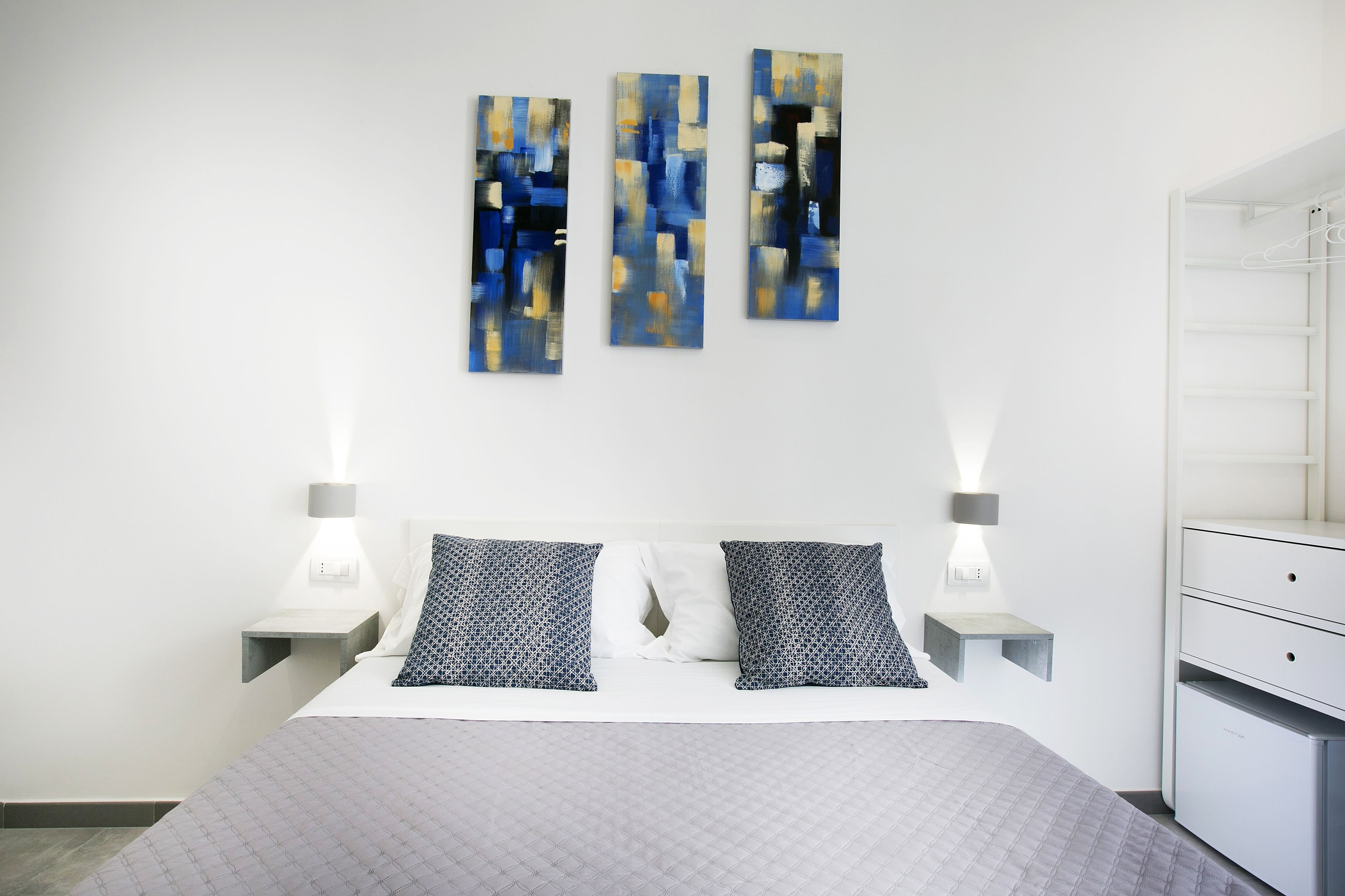 A modern bedroom with a bed, bedside tables, and a wardrobe.