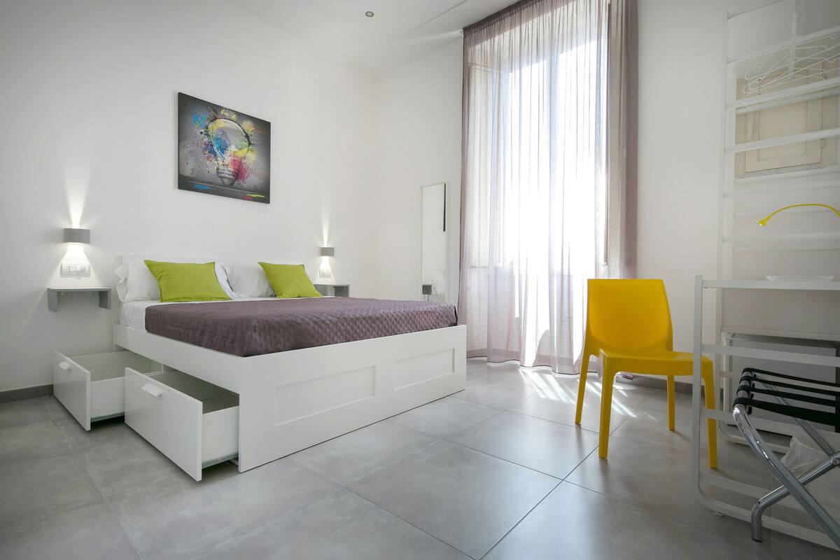 A modern bedroom with a bed, bedside tables, a chair, and a desk.