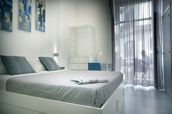 A modern bedroom with a bed, a wardrobe, and a desk.