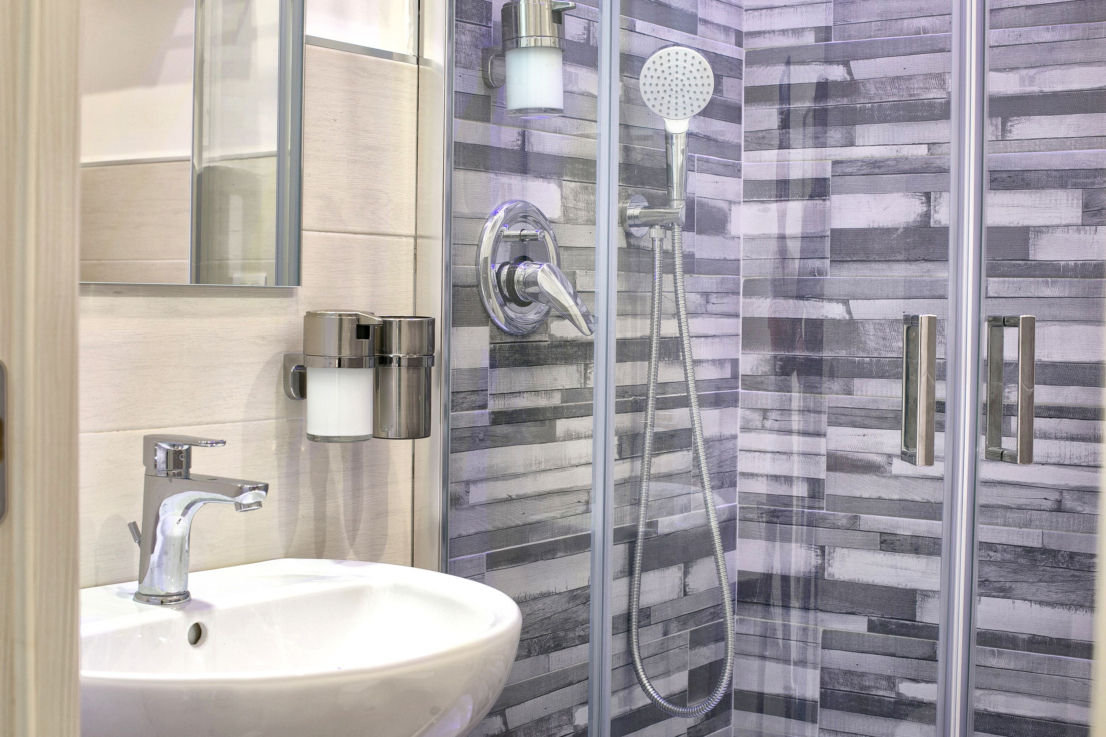 A modern bathroom with a glass-enclosed shower, a white sink, and a mirror.