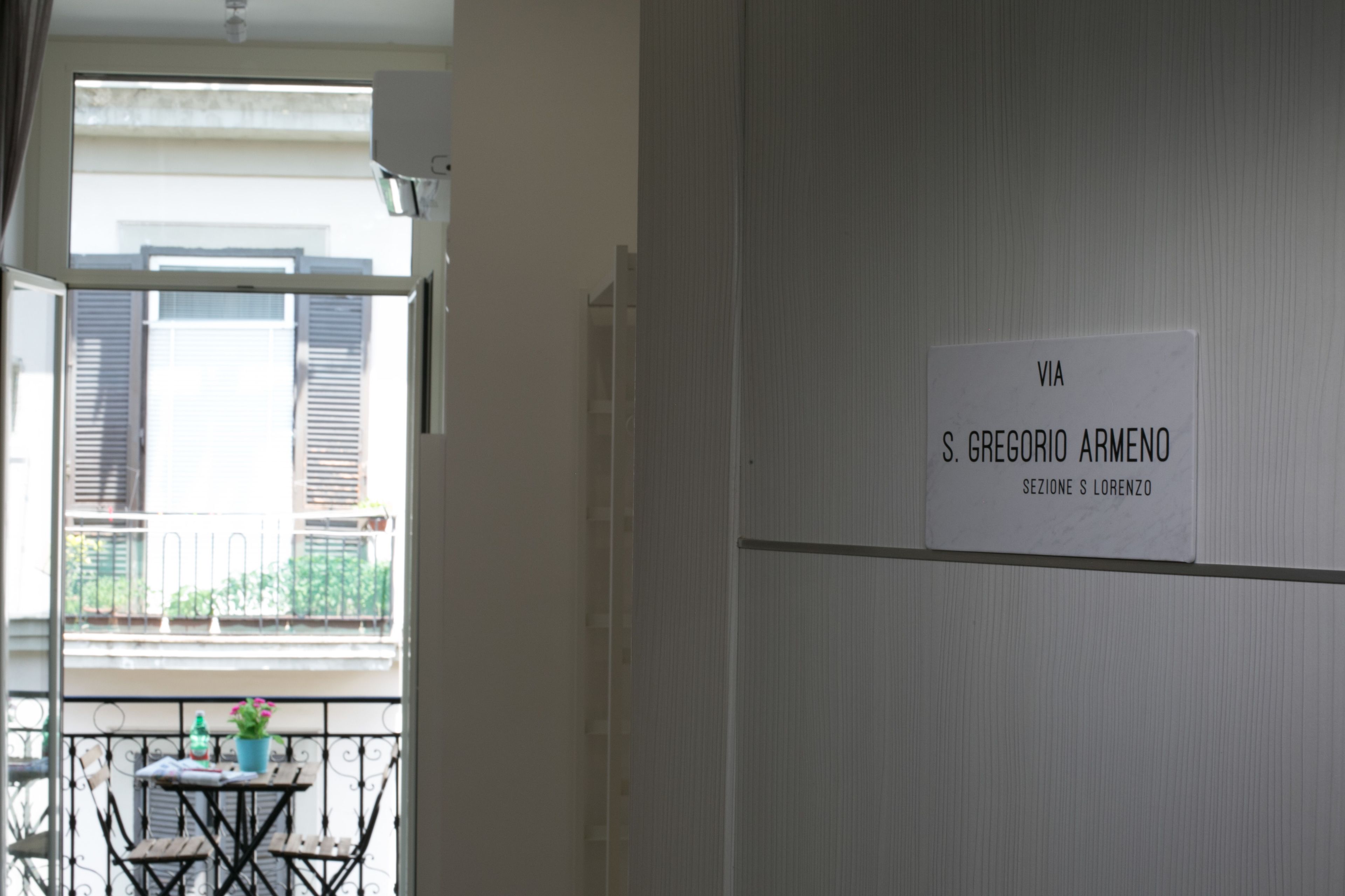 A room with a balcony, a table with chairs, and a sign on the wall.
