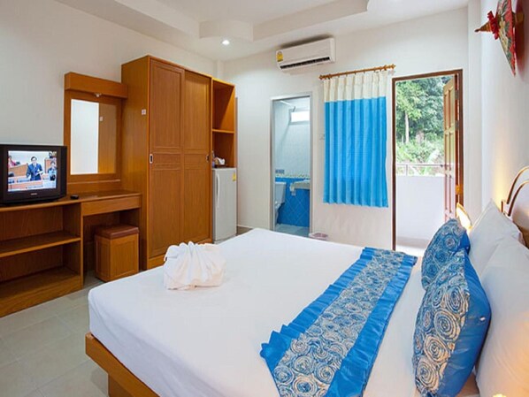 A hotel room with a bed, a TV, a wardrobe, and a bathroom visible through an open door.