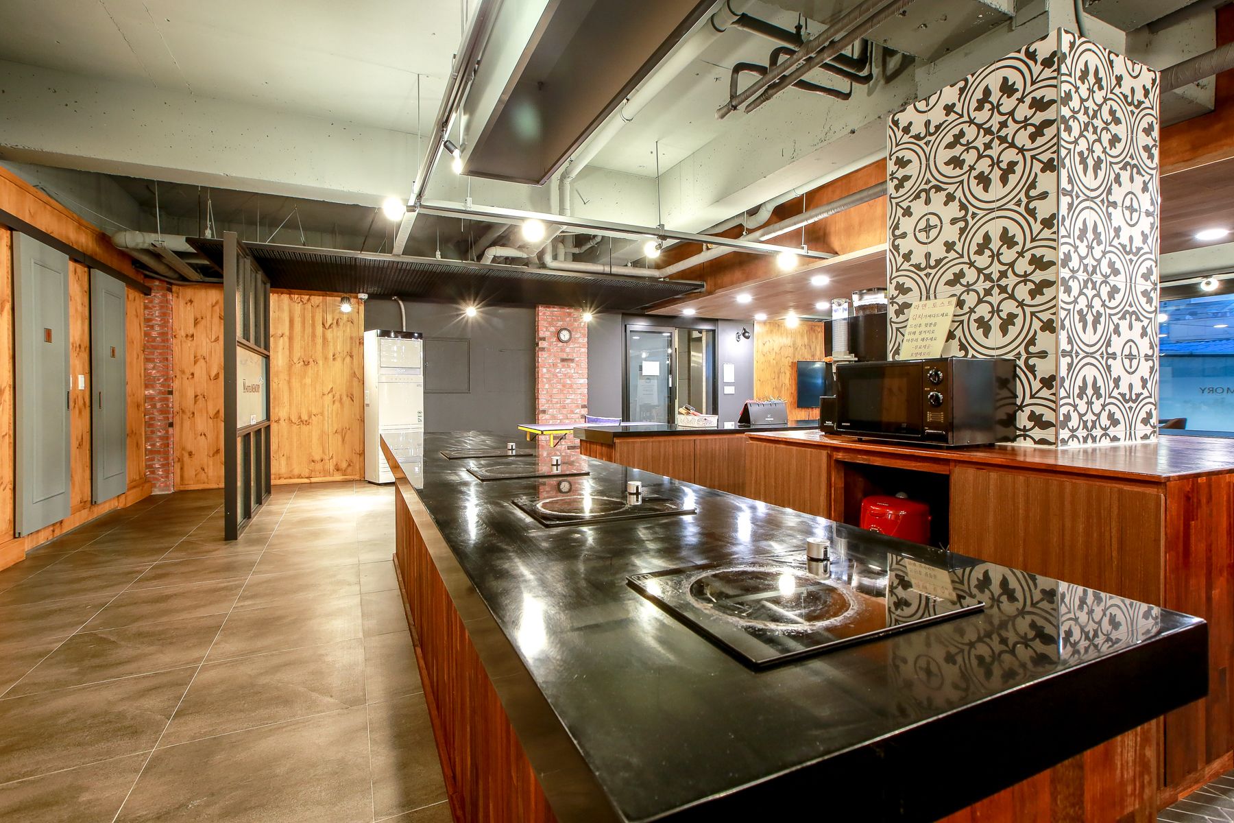 A modern kitchen with a long counter, built-in appliances, and a patterned wall.