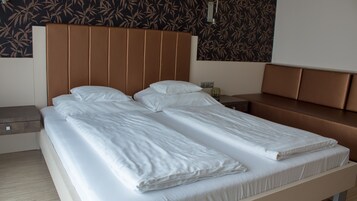 Cama de casal com lençóis brancos em quarto de hotel.