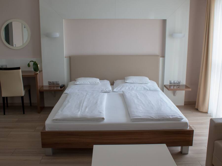 A hotel room with a large bed, a desk, a chair, and a small table.