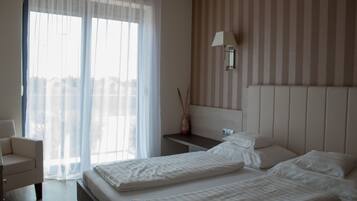A hotel room with a bed, a bedside table, a lamp, and a chair.