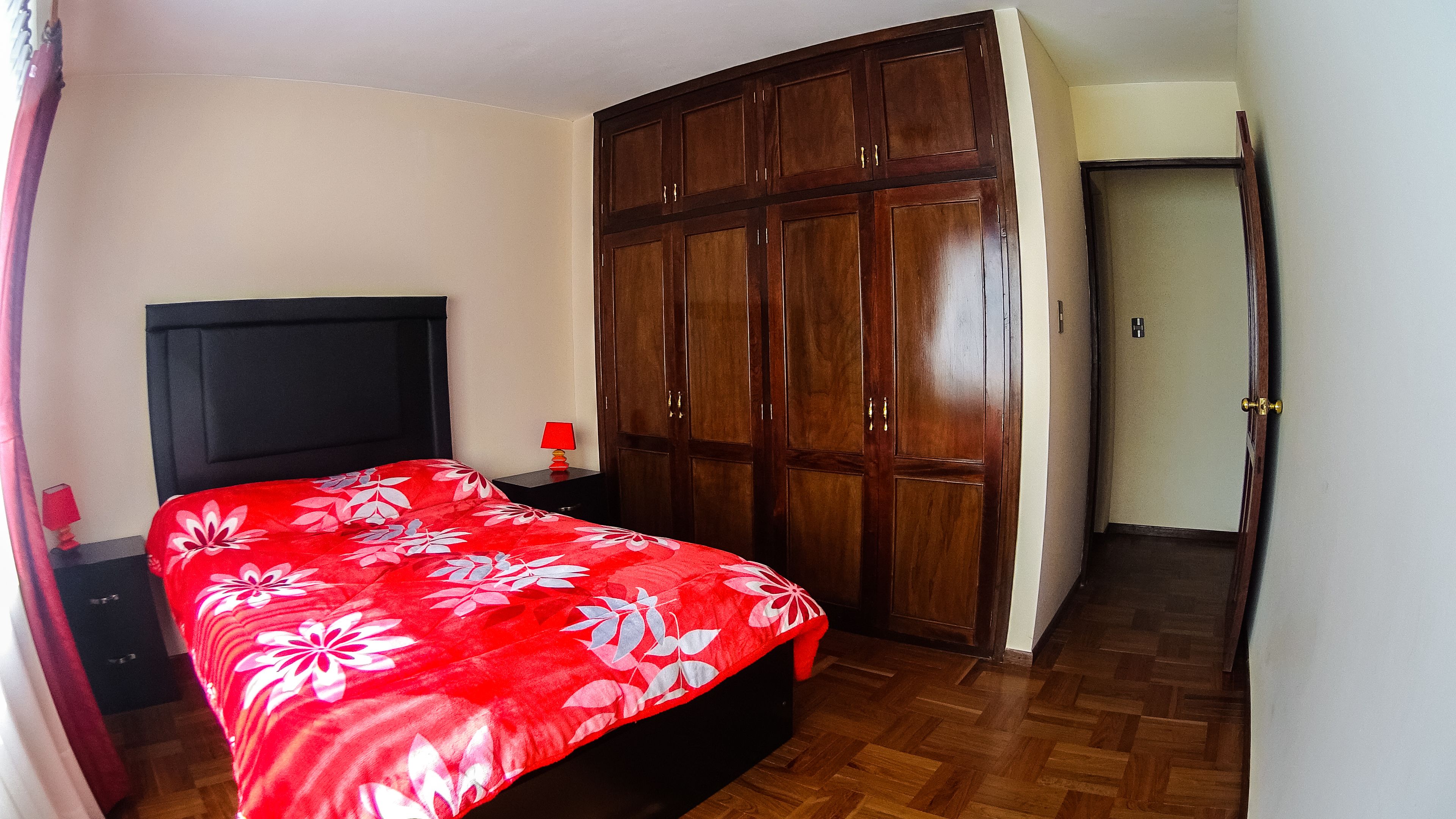 A bedroom with a bed, a wardrobe, and a nightstand.