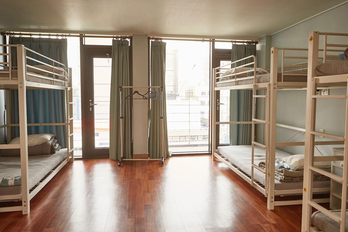 Une chambre avec des lits superposés, un plancher en bois et une porte-fenêtre coulissante donnant sur un balcon.