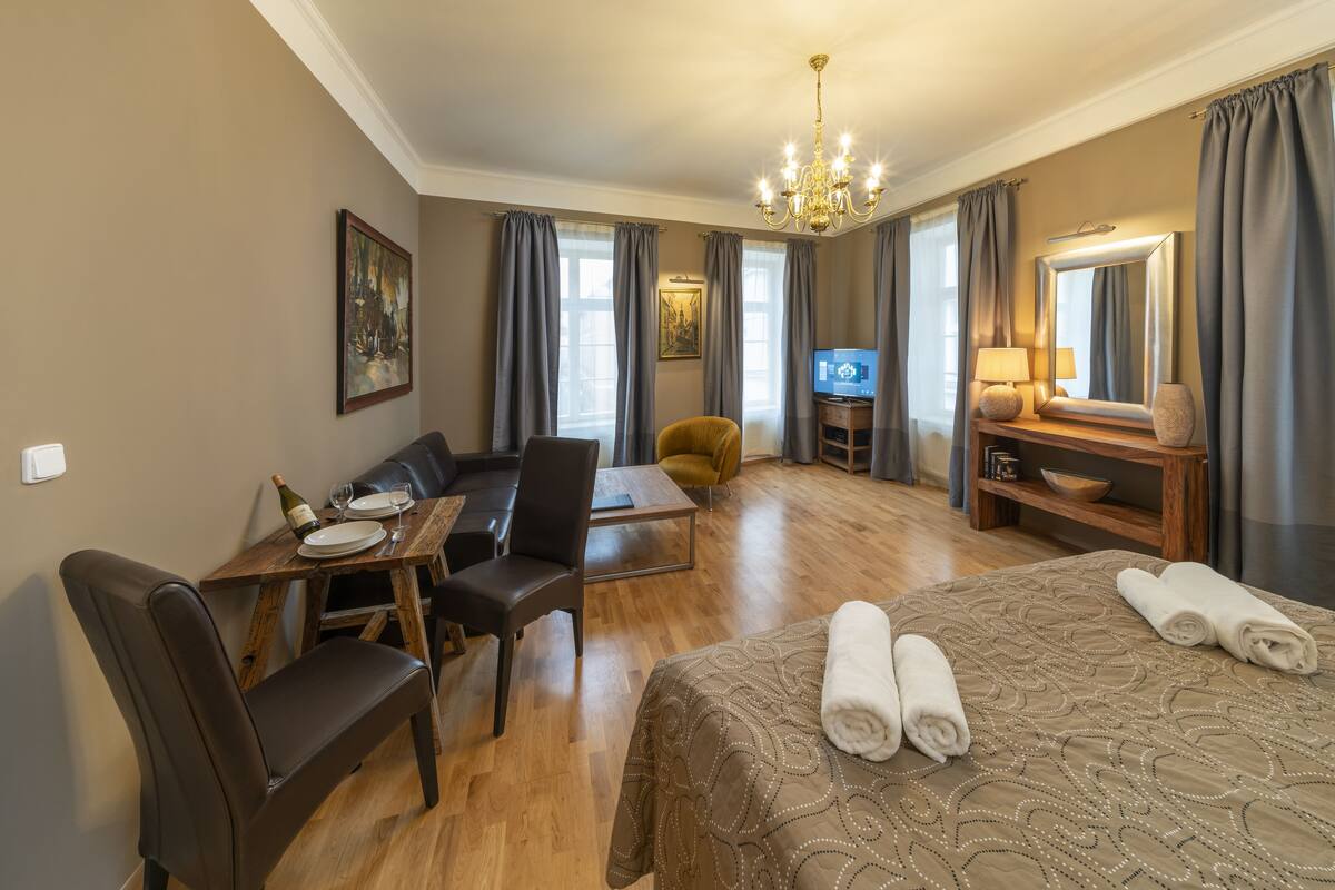 Ein Hotelzimmer mit einem Bett, einer Couch, einem Esstisch mit Stühlen, einem Fernseher und einem kleinen Tisch mit einer Lampe und Dekoration.