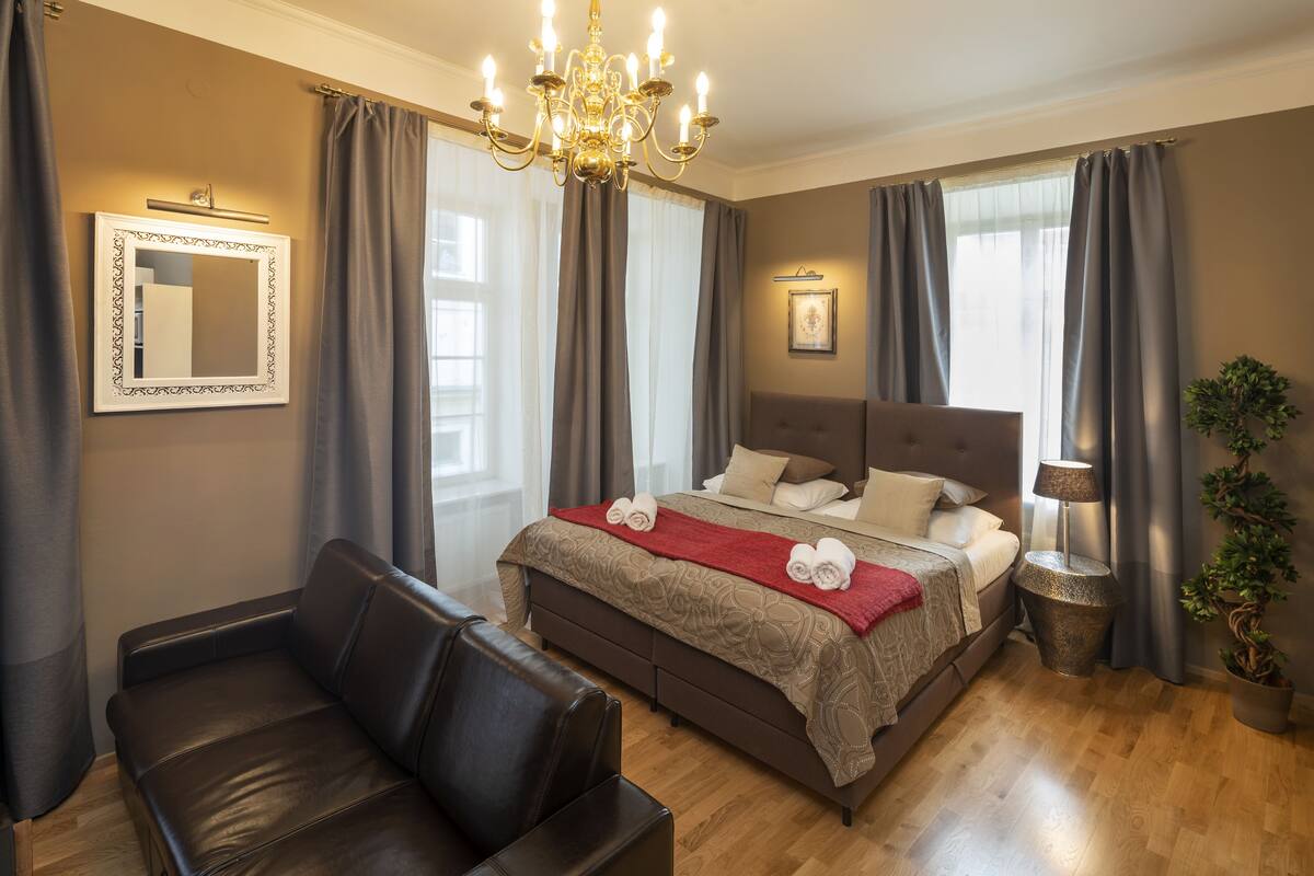 Ein Schlafzimmer mit einem großen Bett, einer Ledersofa, einer Kristallleuchter und einer Topfpflanze.
