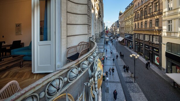 Blick auf ein Gebäude mit Balkon, Kopfsteinpflasterstraße und Fußgänger.