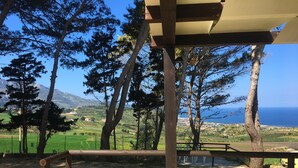 A wooden pergola with a view of a coastal landscape, including trees and a distant view of the sea. - Villa Panoramica Sul Mare (Valderice)