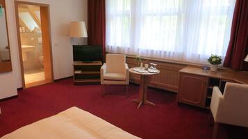 A hotel room with a bed, a desk, a chair, a television, and a window with curtains.