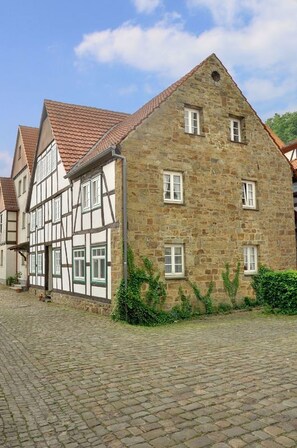 A traditional half-timbered building with a stone facade and a tiled roof, situated on a cobblestone street. - Hotel Schwalenberger Malkasten (Schieder-Schwalenberg)