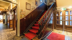 A staircase with red carpeted steps leading to a door with glass panels. - Hotel Schwalenberger Malkasten (Schieder-Schwalenberg)