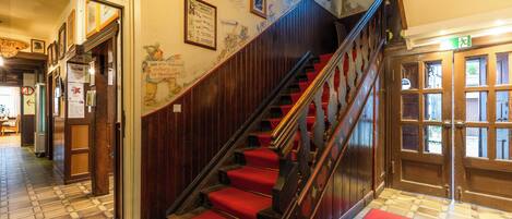 A staircase with red carpeted steps leading to a door with glass panels.