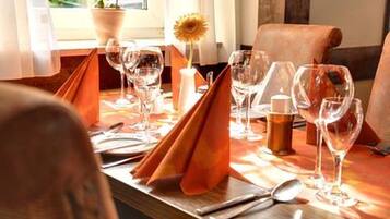 Una mesa de comedor dispuesta con varias copas de vino, una vela y un florero con una flor.