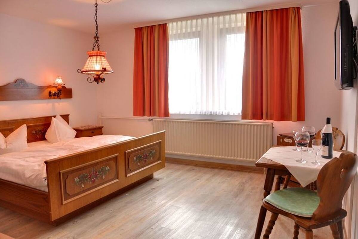 Ein Schlafzimmer mit einem hölzernen Bett, einem Tisch mit Weingläsern und einer Heizung.