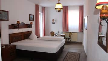 A hotel room with a large bed, a desk, a chair, and a small table.