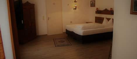Un dormitorio con cama, armario, puerta, lámpara de pared y una pequeña alfombra.