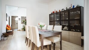 Un coin repas avec une table en bois, des chaises blanches et un buffet noir doté de portes en verre.