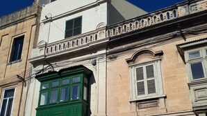 Un bâtiment avec une fenêtre verte, une porte blanche et une façade beige.