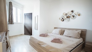 Une chambre à coucher avec un lit en bois, une table de chevet, une œuvre d’art murale et une fenêtre avec des rideaux.