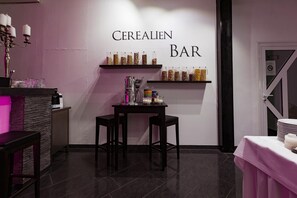 A bar area with shelves displaying various cereals, a bar counter, and stools. - Hotel Rühen 24-hour check-in, free parking, guest kitchen (Rühen)