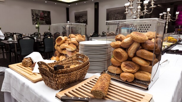 A buffet setup with various breads, a cutting board, and a knife on a table. - Hotel Rühen 24-hour check-in, free parking, guest kitchen (Rühen)