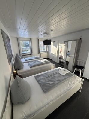 A modern hotel room with two single beds, a TV, a mirror, and a window with a view of the outside. - Hotel Rühen 24-hour check-in, free parking, guest kitchen (Rühen)