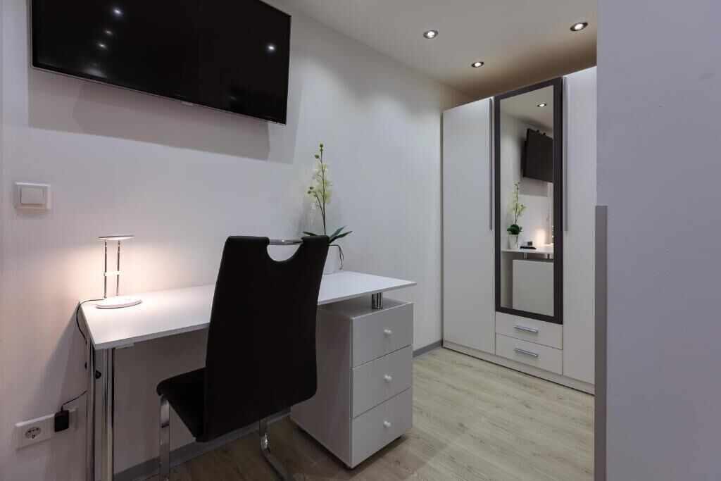 Un dormitorio moderno con escritorio, silla y un espejo grande.