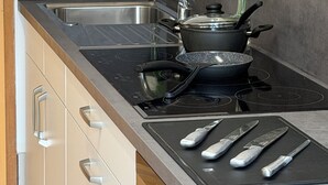 A kitchen with a stove, sink, and a vase with flowers. - Hotel Rühen 24-hour check-in, free parking, guest kitchen (Rühen)