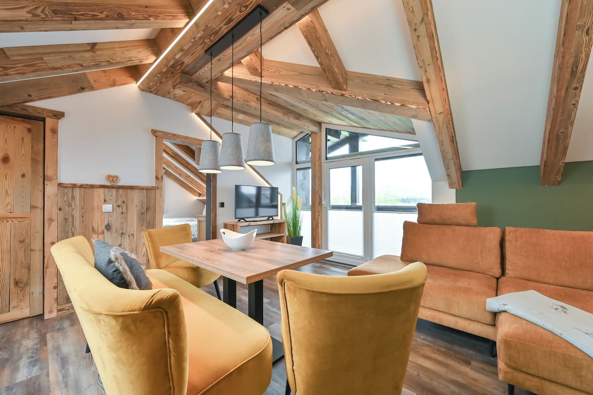 A modern interior with wooden beams, a dining area with yellow chairs, and a sofa.