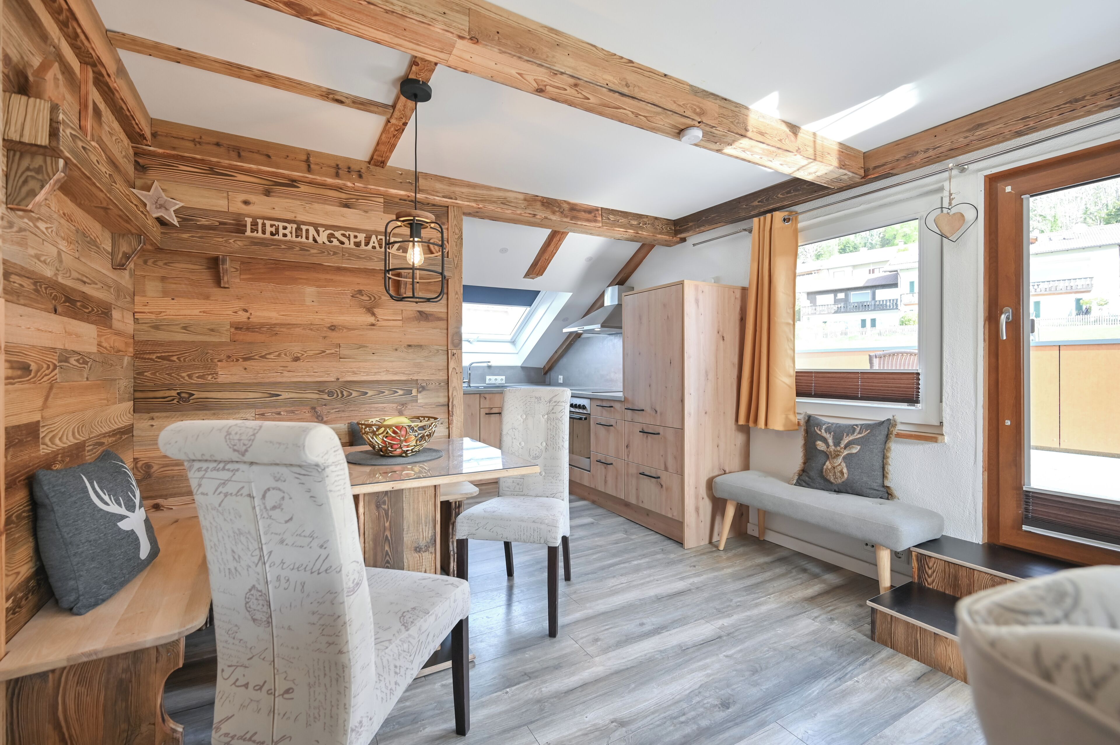Un interior acogedor con paredes de madera, un comedor con banco y una cocina al fondo.