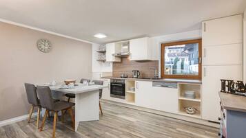 Una cucina moderna con mobili bianchi, forno integrato e finestra con vista sulla strada.