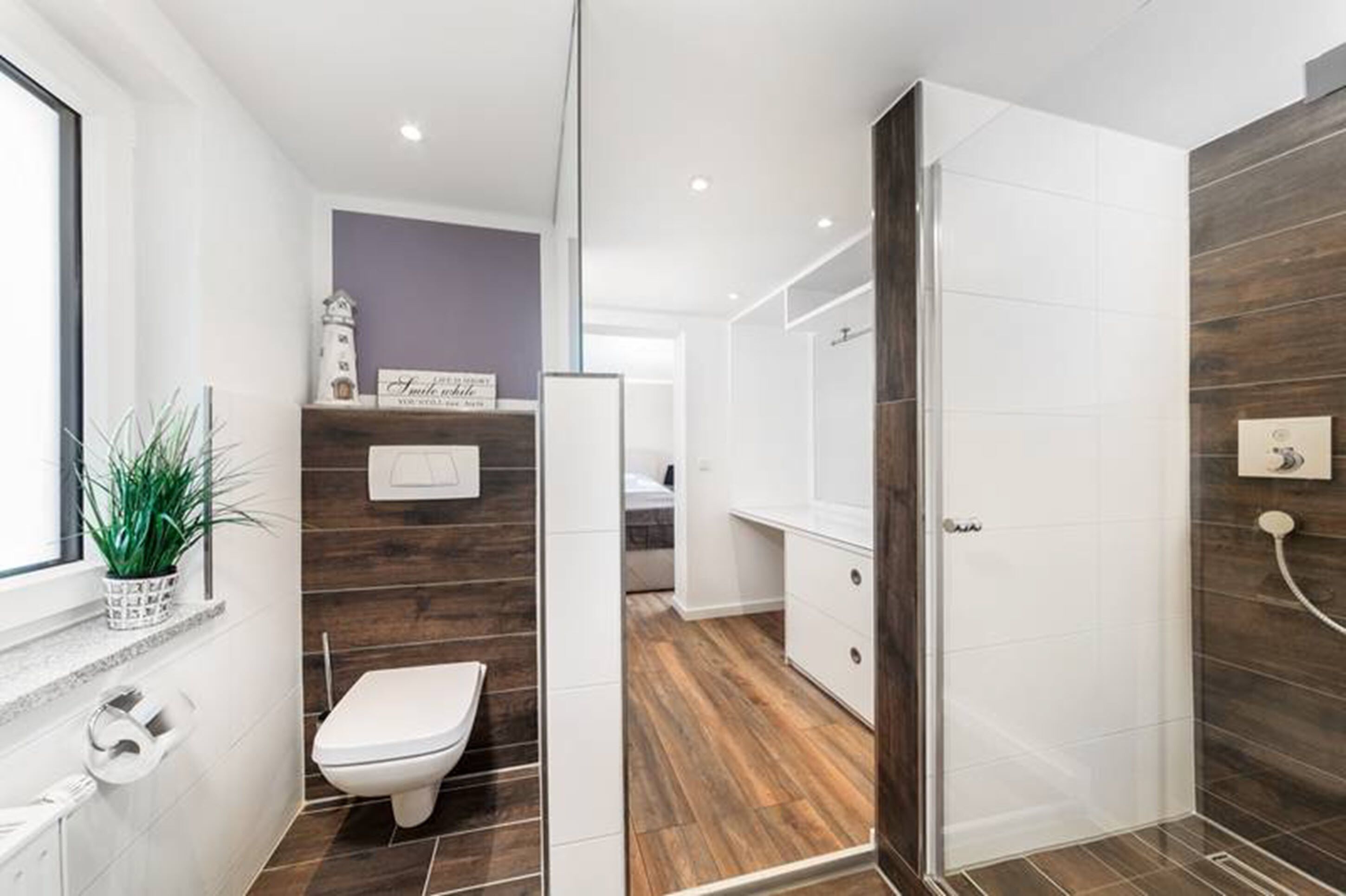 A modern bathroom with a toilet, a shower area, and a vanity with a mirror.