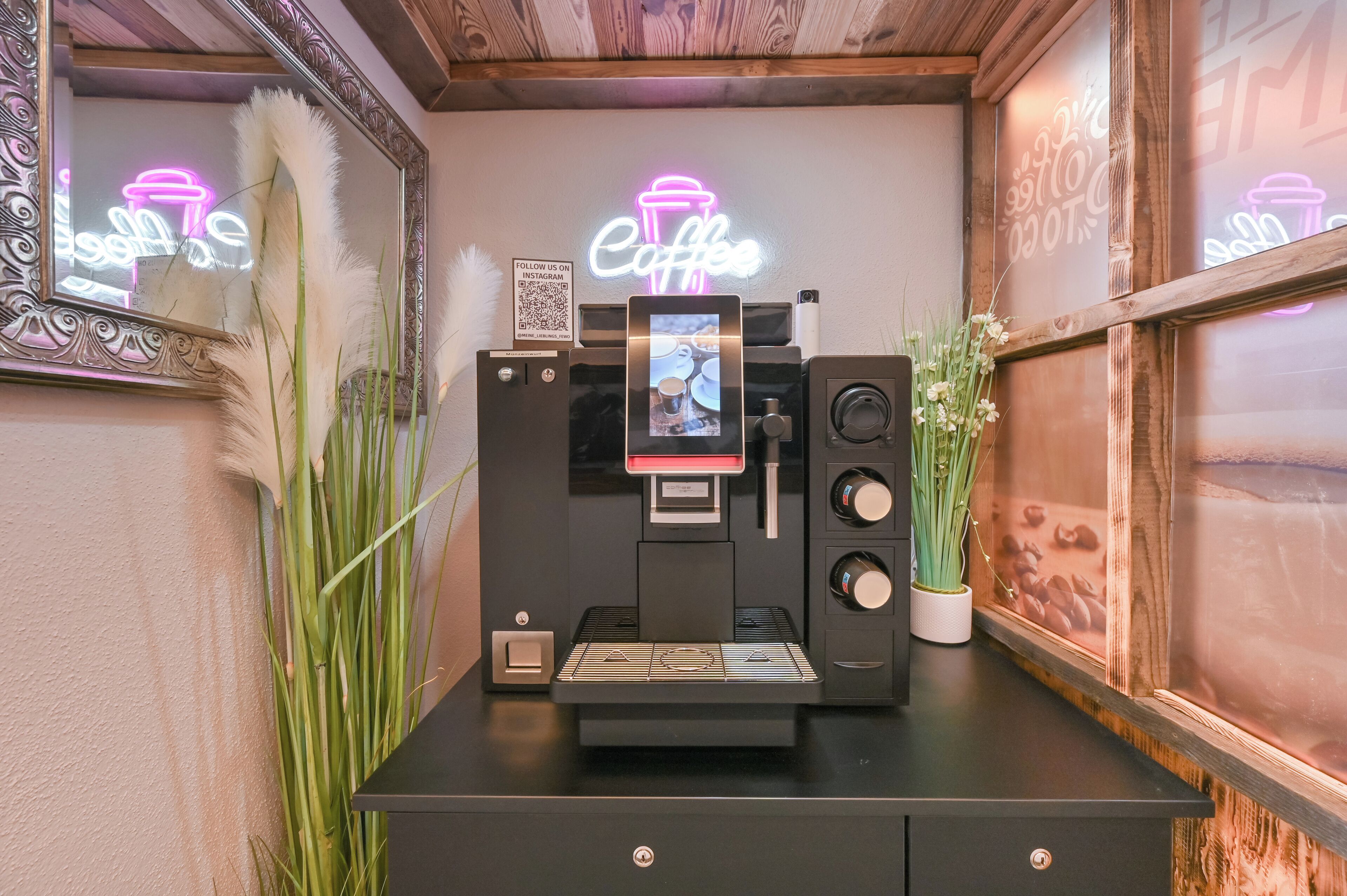 A coffee machine with a neon sign, a mirror, and decorative plants.