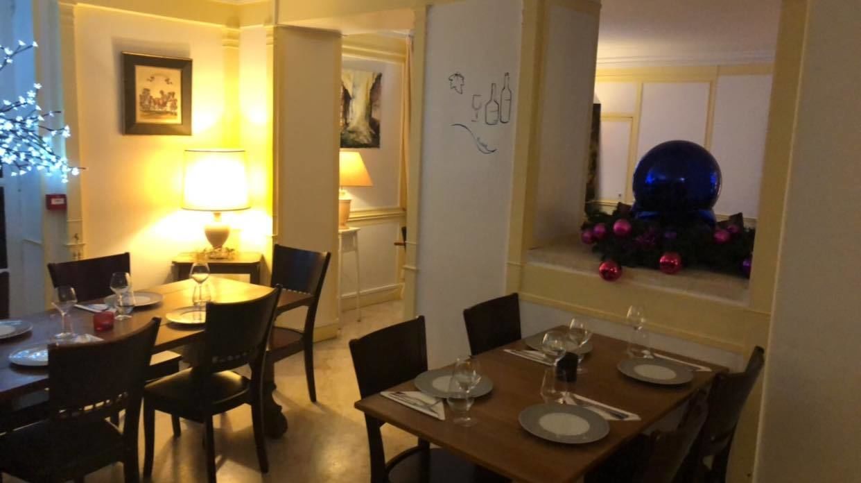 Een eethoek met een tafel voor twee, een lamp en een muur met een afbeelding van een wijnfles.